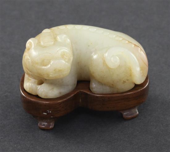 A Chinese pale celadon and russet jade recumbent figure of a bixi, 19th century, 5cm, wood stand